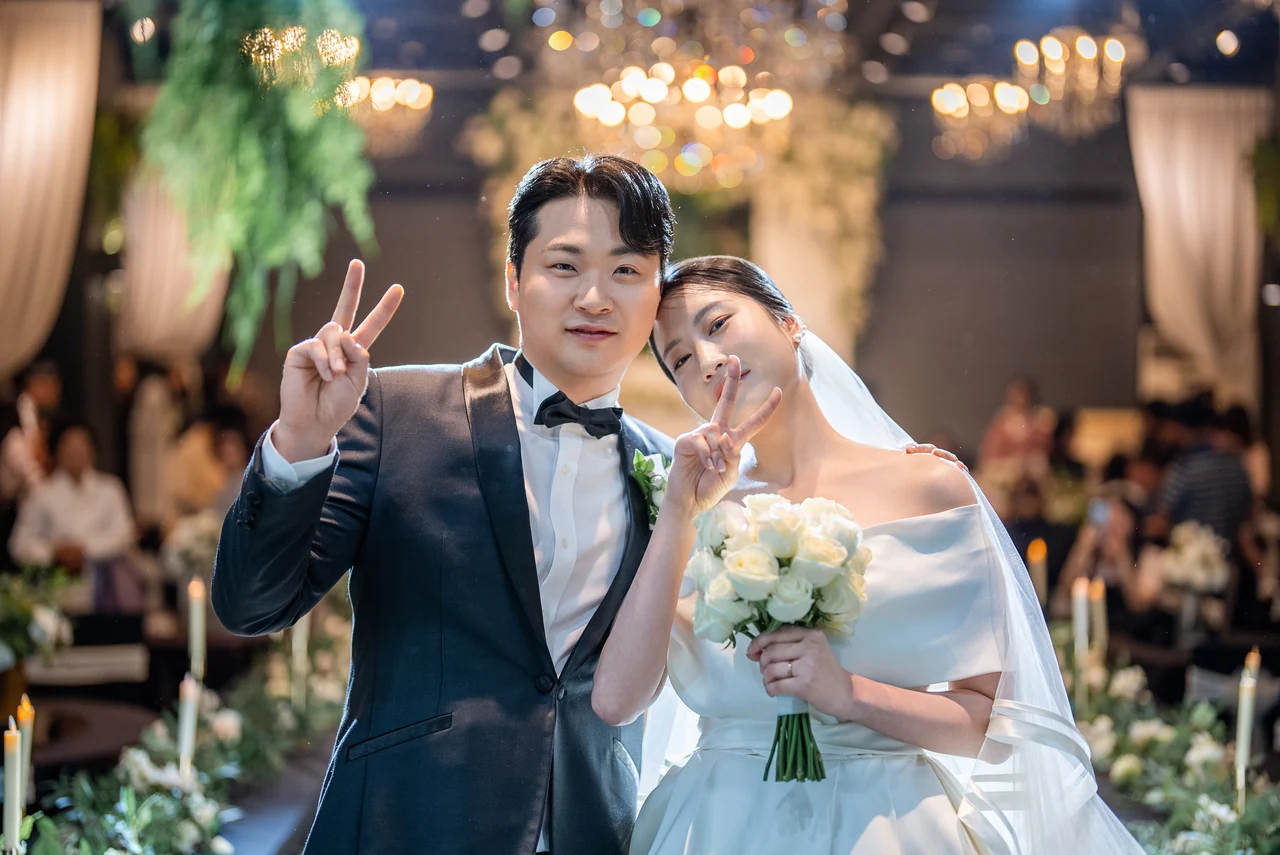 따뜻한 조명 아래 나란히 서 있는 신랑과 신부
